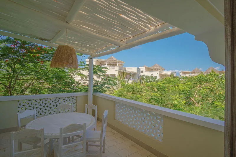 Villa Bobo's covered terrace with a dining table, looking over the treetops to the sea