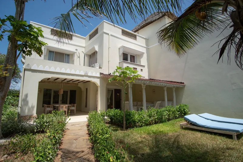 Villa Lollo's two-storey white exterior, lawn and sun loungers