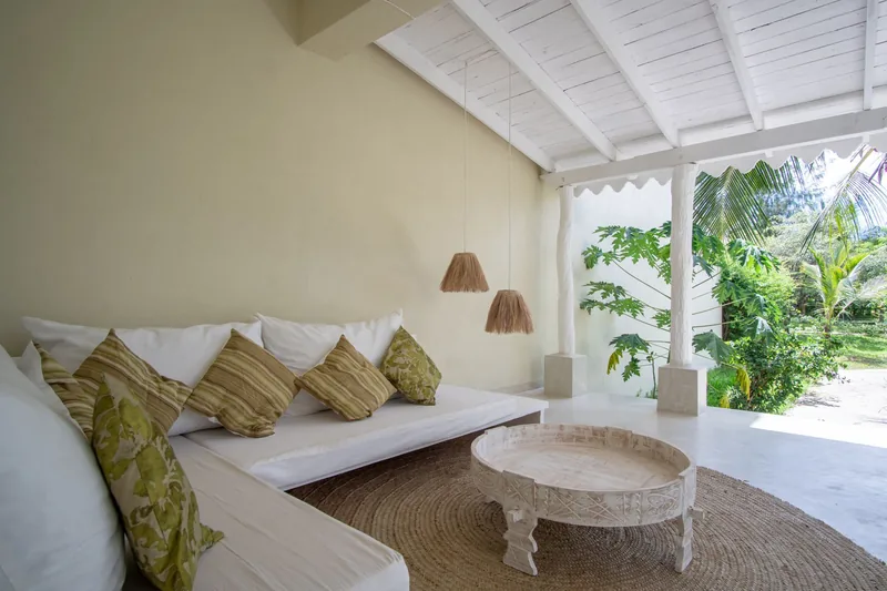 Margi Villa's covered veranda lounge with white sofas and a garden view