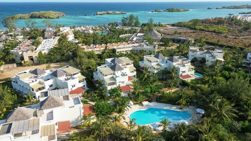 Aerial view of the villas and shared pool at Papa Remo Village, with the bay beyond