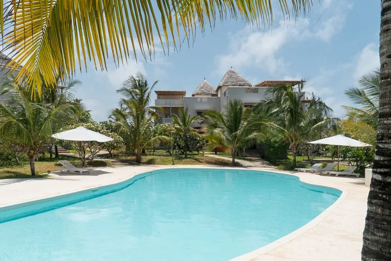 The shared pool at Papa Remo Village with a makuti-roofed building behind
